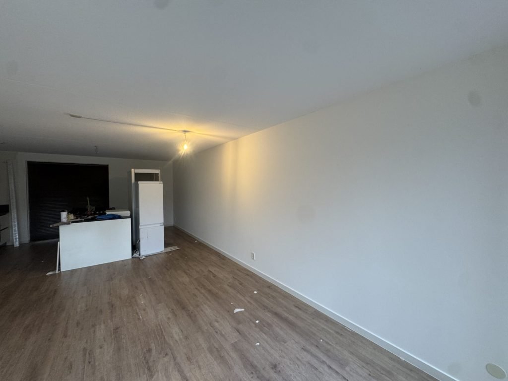Lange witte wand in een woonkamer waar het licht van een lamp schuin langs de muur valt